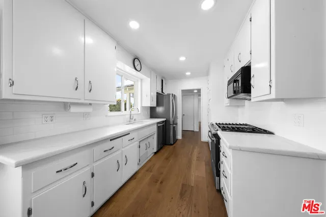 a large kitchen with kitchen island a large counter space a sink stainless steel appliances and cabinets