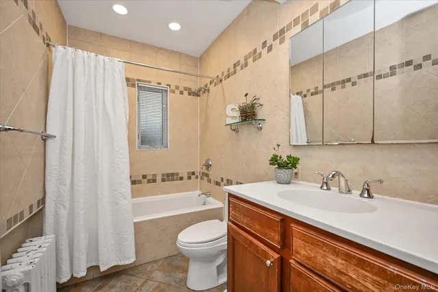 a bathroom with a sink a toilet a mirror a bathtub and shower