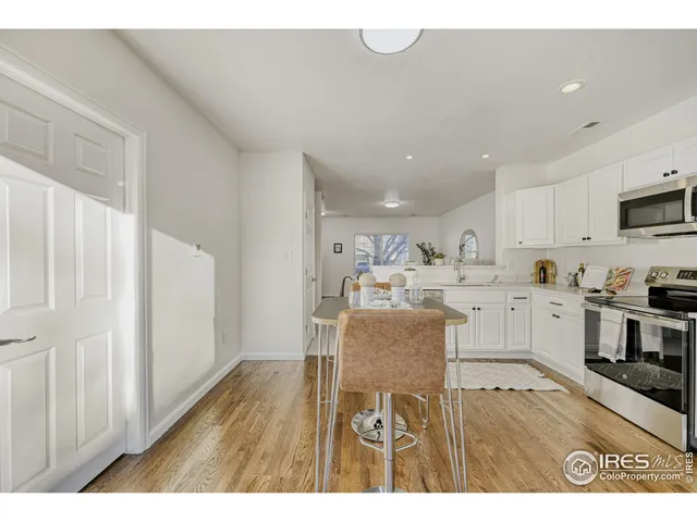 a kitchen with stainless steel appliances granite countertop a refrigerator a stove top oven a sink and dishwasher with wooden floor