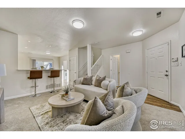 a living room with furniture a rug and kitchen view