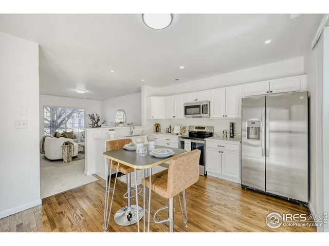 a kitchen with stainless steel appliances kitchen island granite countertop a refrigerator a stove a sink dishwasher and white cabinets with wooden floor