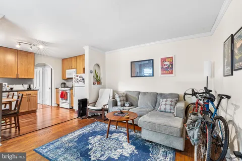 a living room with furniture kitchen view and a wooden floor