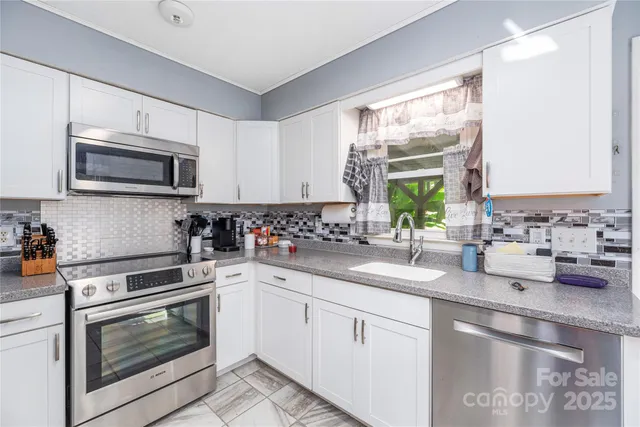 a kitchen with granite countertop white cabinets appliances and a sink