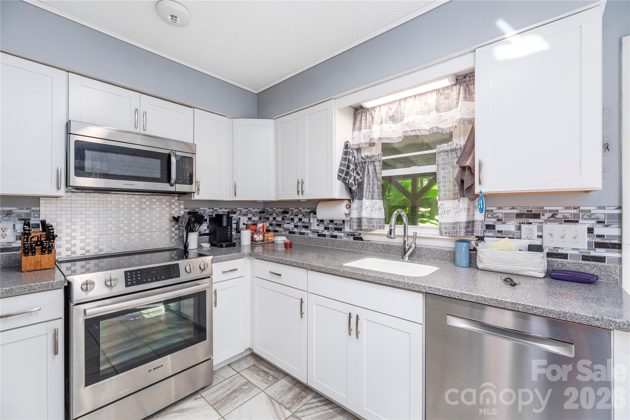 29 Arrowhead Street Clyde, NC 28721 - Photo 6 of 18 a kitchen with granite countertop white cabinets appliances and a sink