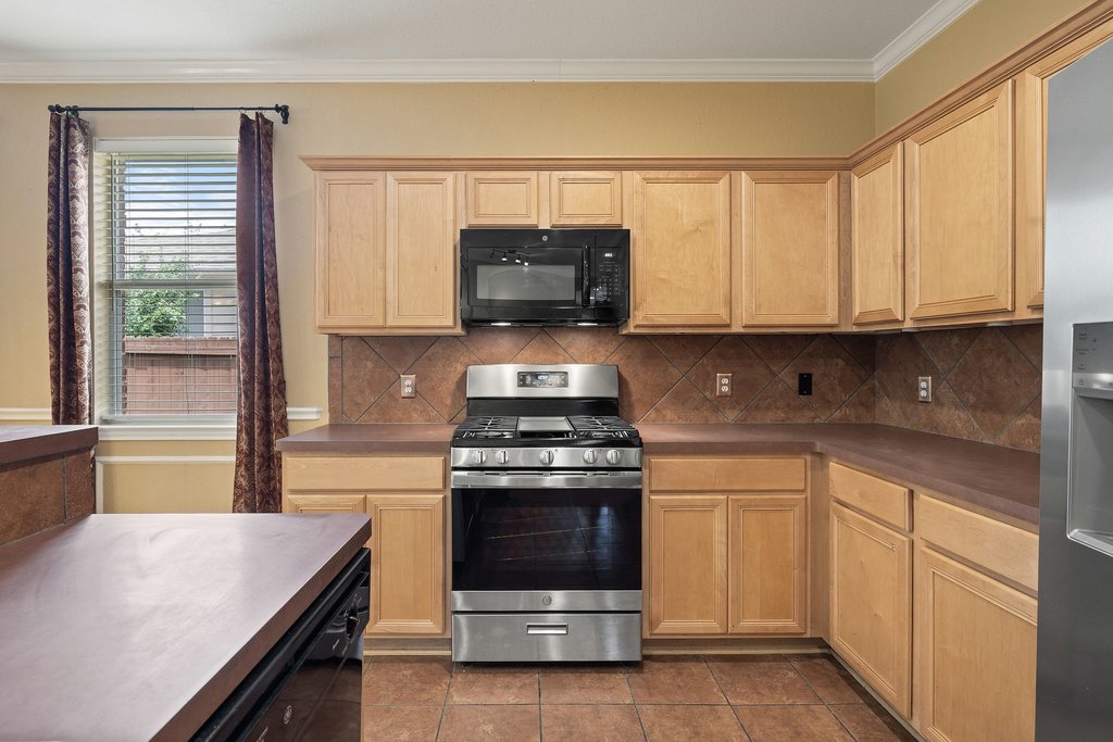 347 Spring Drive Kyle, TX 78640 - Photo 10 of 40 A well-equipped kitchen features a gas range and tile flooring, ready for culinary endeavors.