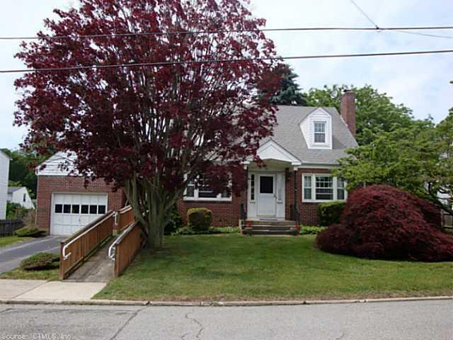 a front view of a house with a garden and trees