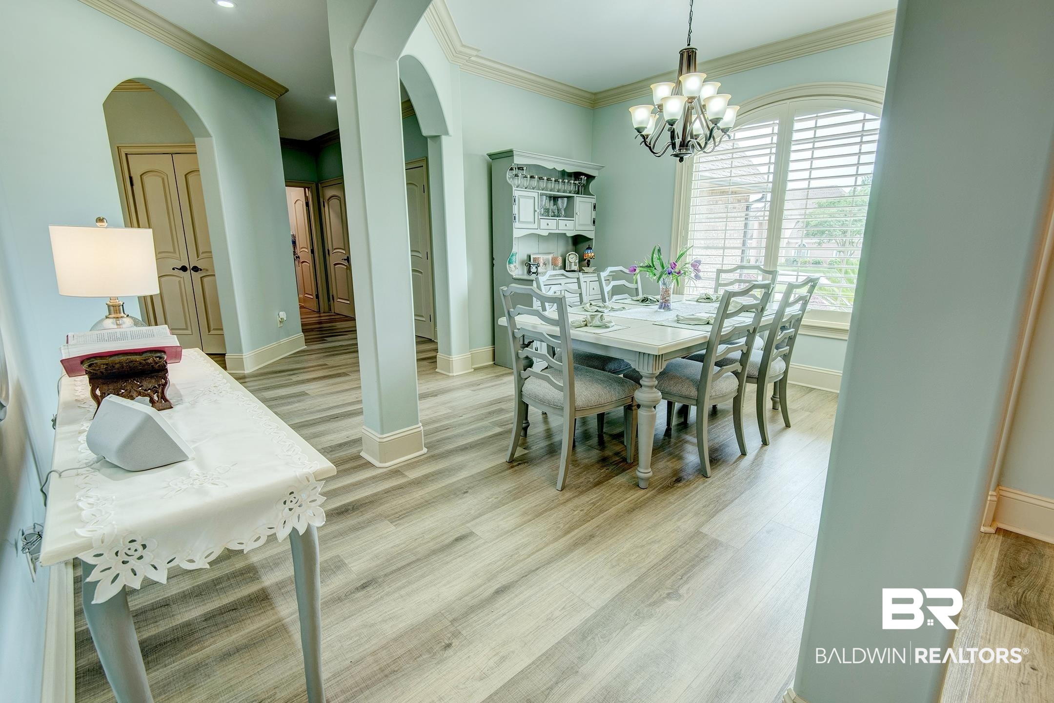 9357 Lakeview Drive Foley, AL 36535 - Photo 27 of 68 Dining area featuring wood-finish flooring, a large arched window with plantation shutters, an overhead chandelier, and decorative arched doorways
