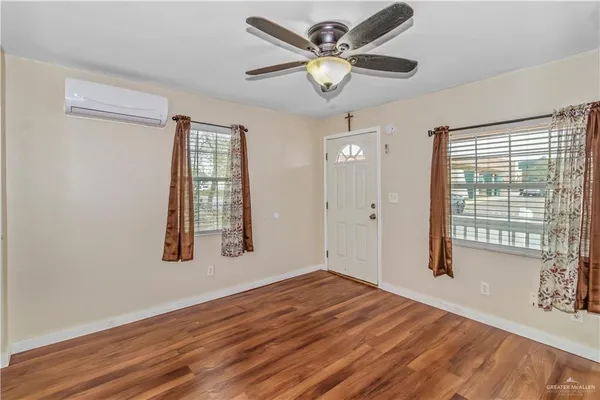 a view of an empty room with a window and wooden floor