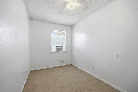 an empty room with a chandelier fan and windows