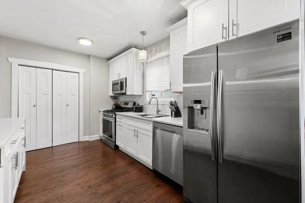 a kitchen with stainless steel appliances granite countertop a refrigerator a sink and white cabinets