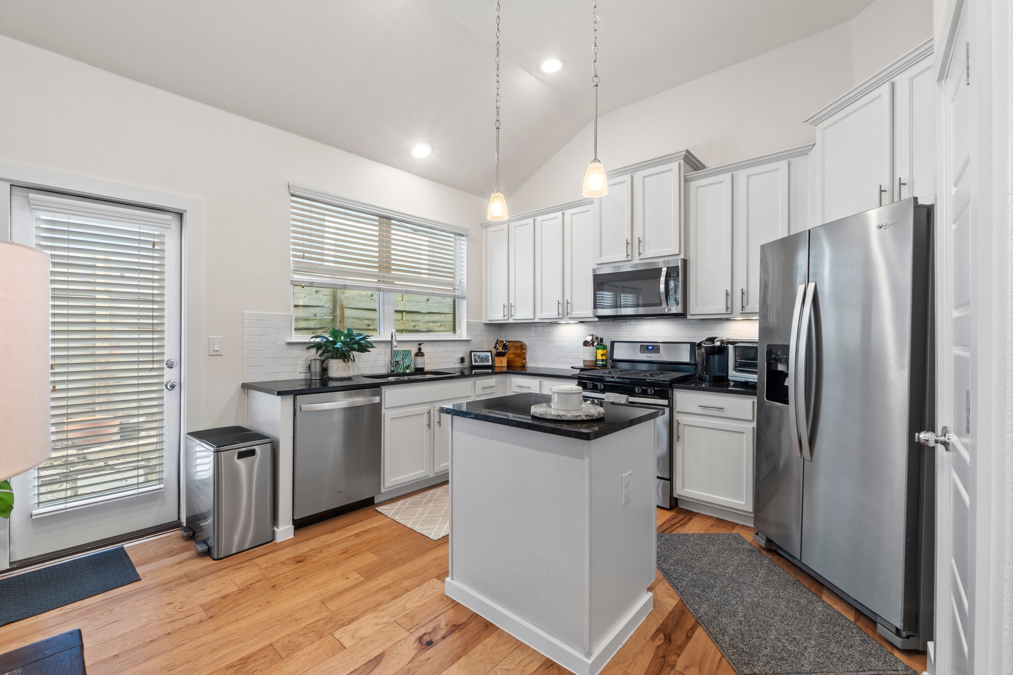 2100 Hermia Street, Unit 41 Austin, TX 78741 - Photo 5 of 22 a kitchen with stainless steel appliances granite countertop a refrigerator a sink dishwasher a stove a refrigerator and white cabinets with wooden floor
