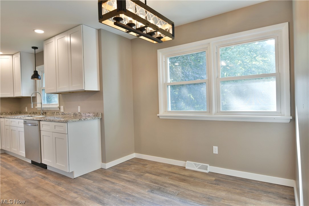 5480 Phillips Rice Road Cortland, OH 44410 - Photo 5 of 35 Kitchen featuring stainless steel dishwasher, light countertops, light hardwood floors, and white cabinets