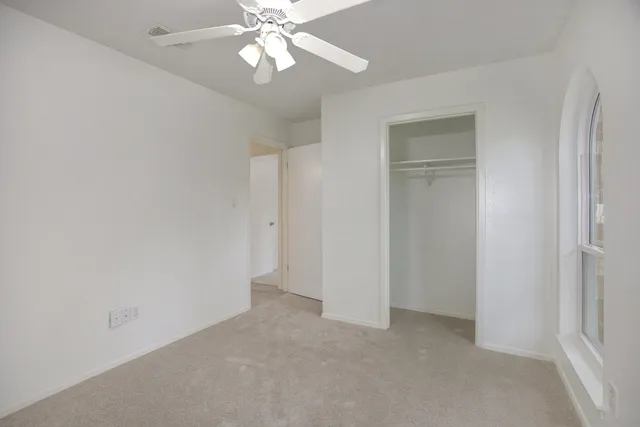 a view of an empty room and chandelier fan