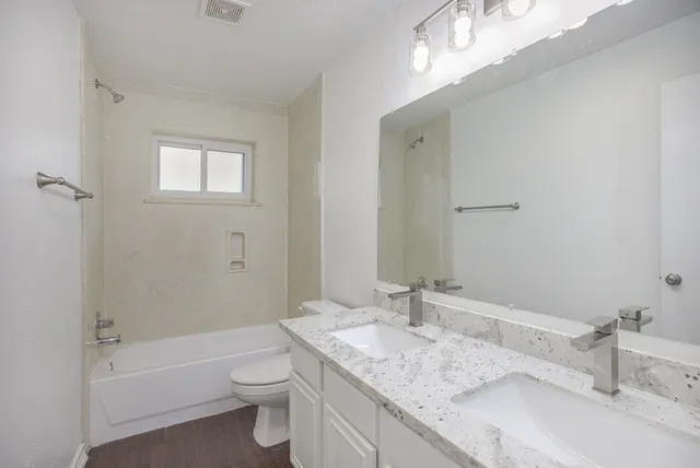 a bathroom with a granite countertop sink a toilet and bathtub