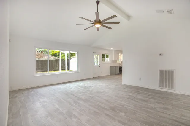 a view of an empty room with a window and wooden floor