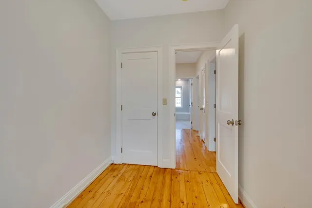 a view of a hallway with wooden floor and a bathroom