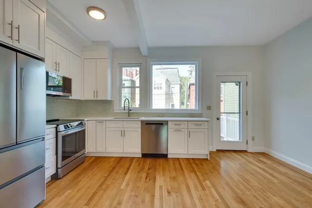 a kitchen with granite countertop white cabinets and wooden floor