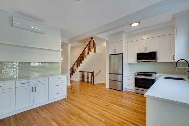 a kitchen with stainless steel appliances wooden floor and a refrigerator