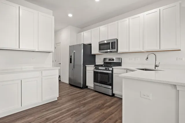 a kitchen with cabinets stainless steel appliances and wooden floor