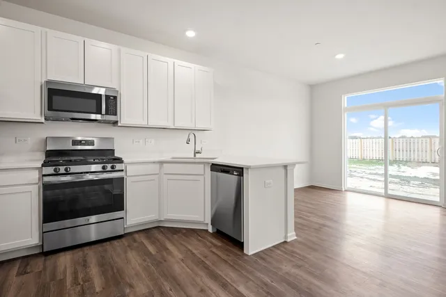 a kitchen with stainless steel appliances granite countertop a stove a sink and a microwave