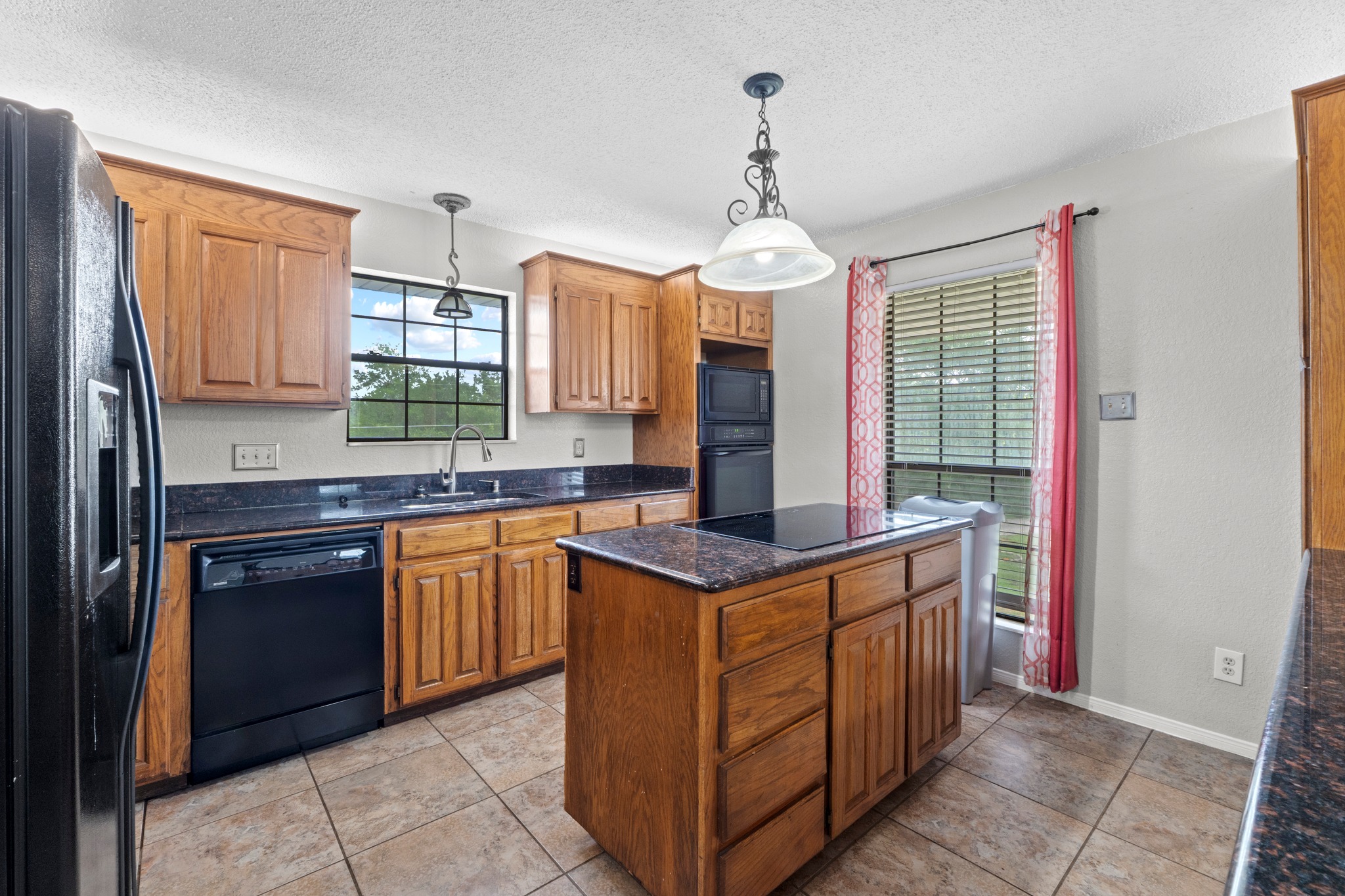 205 Sedro Trail Georgetown, TX 78633 - Photo 15 of 32 A functional kitchen features ample wood cabinetry, dark countertops, and a central island with a built-in cooktop.