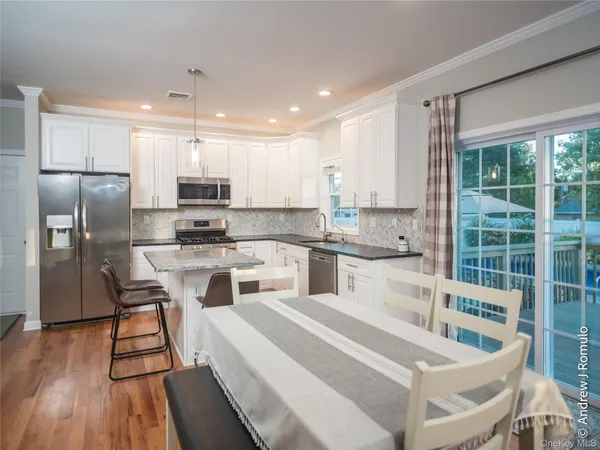 a large kitchen with kitchen island a large counter top space a sink stainless steel appliances and cabinets