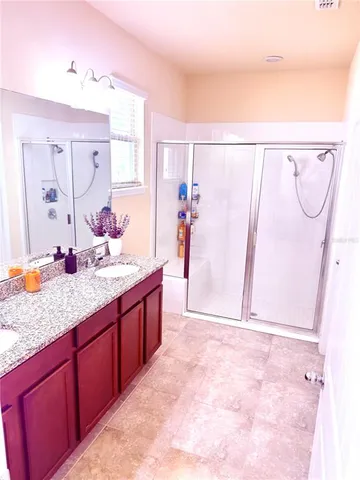 a spacious bathroom with a granite countertop sink a mirror and a shower