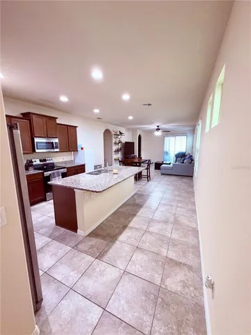 a large kitchen with kitchen island granite countertop a large counter top space a sink a stove a refrigerator and cabinets