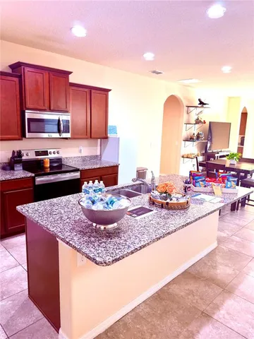 a kitchen with kitchen island granite countertop a sink counter top space a stove and cabinets