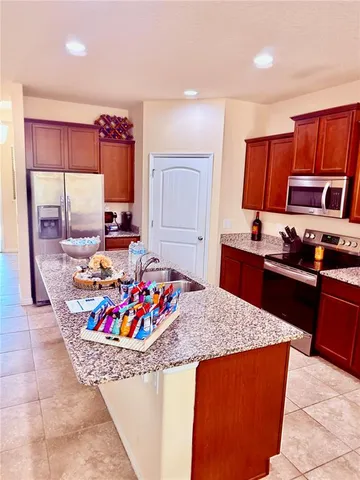 a view of kitchen with stainless steel appliances granite countertop sink stove and granite counter top
