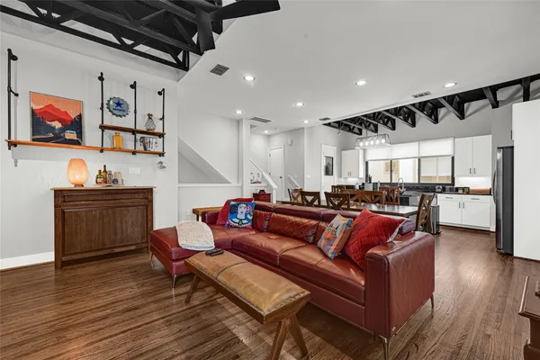 a living room with furniture kitchen view and a wooden floor