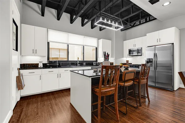 a kitchen with stainless steel appliances a dining table chairs microwave and sink