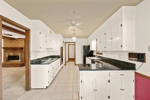a kitchen with granite countertop a stove a sink and a refrigerator