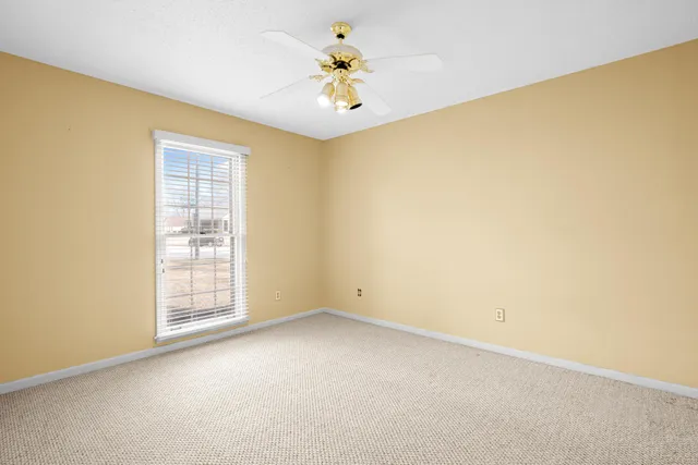 an empty room with windows and chandelier fan