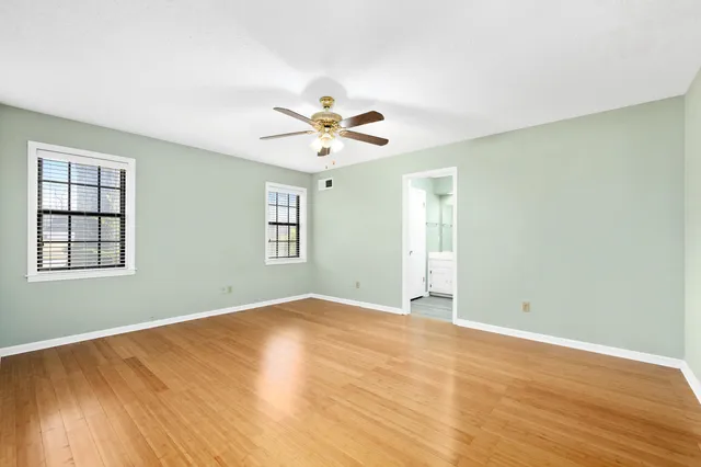 a view of an empty room with chandelier fan and wooden floor