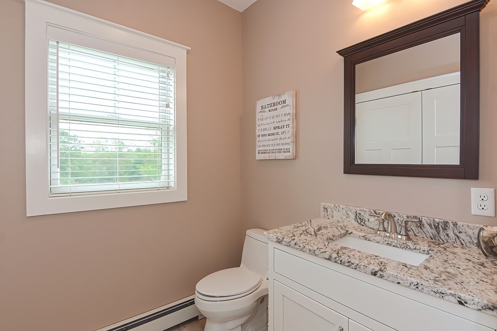 128 Nourse Road Bolton, MA 01740 - Photo 14 of 42 a bathroom with a granite countertop toilet a sink and a mirror