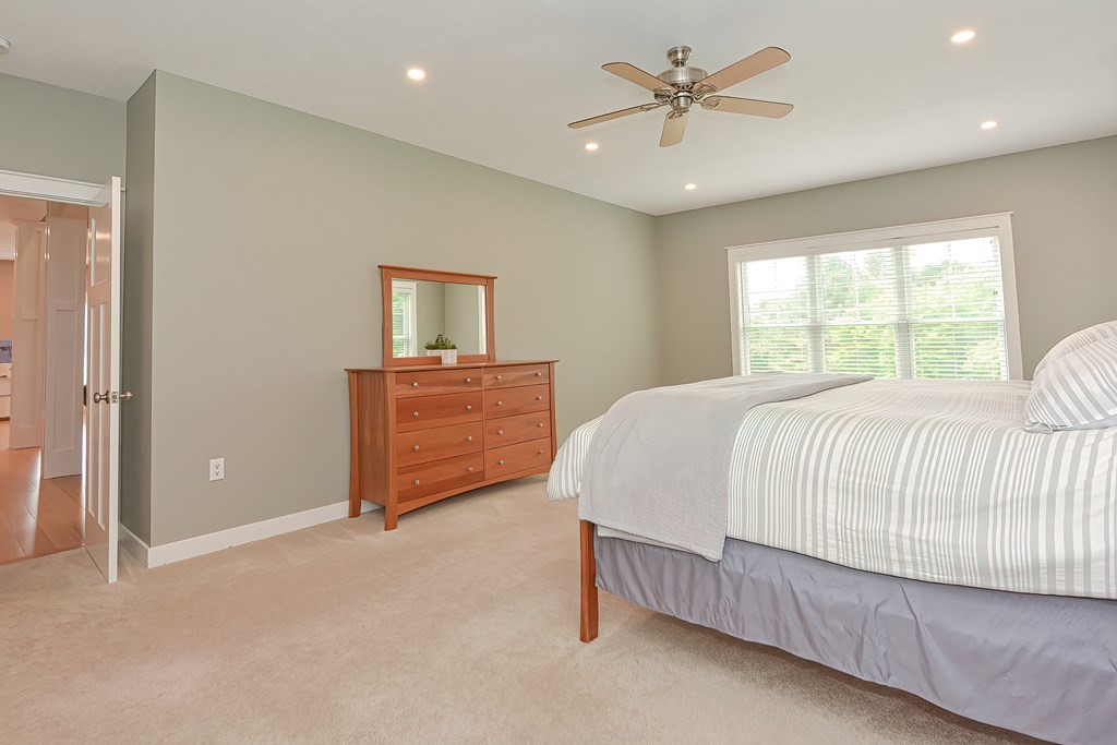 128 Nourse Road Bolton, MA 01740 - Photo 17 of 42 a spacious bedroom with a bed and a chandelier