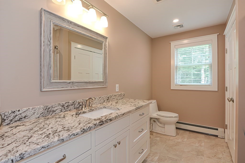 128 Nourse Road Bolton, MA 01740 - Photo 30 of 42 a bathroom with a granite countertop sink toilet and mirror