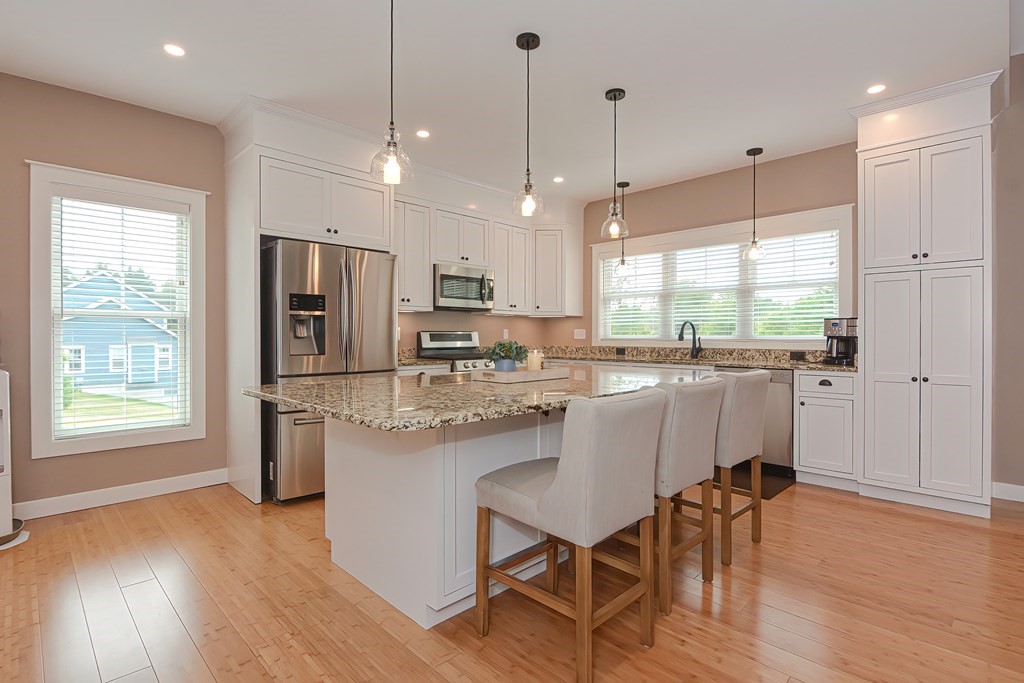 128 Nourse Road Bolton, MA 01740 - Photo 7 of 42 a kitchen with stainless steel appliances granite countertop a refrigerator a stove a sink dishwasher and a dining table with wooden floor