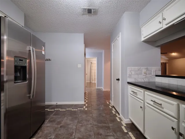 a view of an empty room and window with a chandelier fan