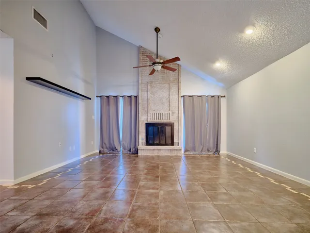 a view of an empty room with a fireplace and a window