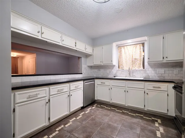 a kitchen with granite countertop a sink stainless steel appliances and cabinets