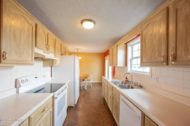 a kitchen with a sink a counter top space cabinets stainless steel appliances and a large window