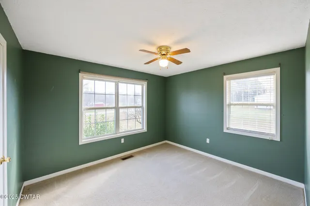 an empty room with a window and a fan