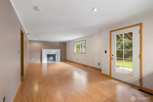 a view of an empty room with a window and wooden floor
