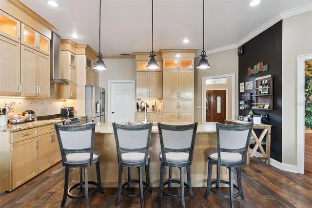 a kitchen with stainless steel appliances granite countertop a refrigerator a sink a stove and white cabinets