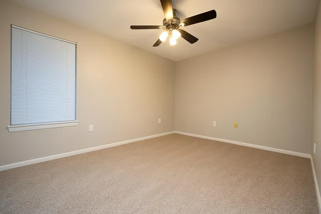 an empty room with a window and a fan
