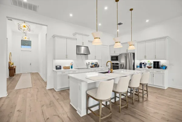 a large kitchen with cabinets chairs and wooden floor