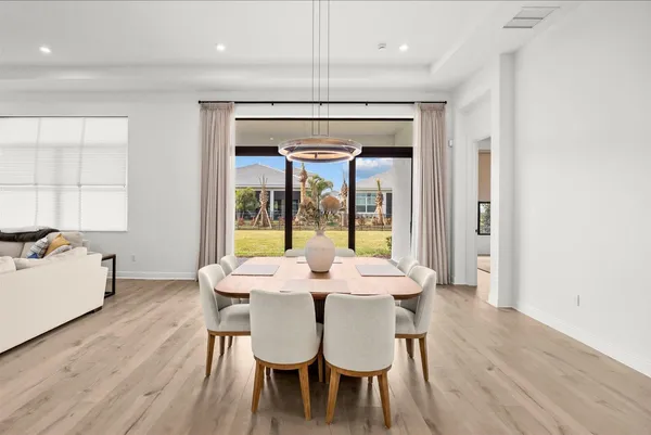 a dining room with furniture a chandelier and wooden floor
