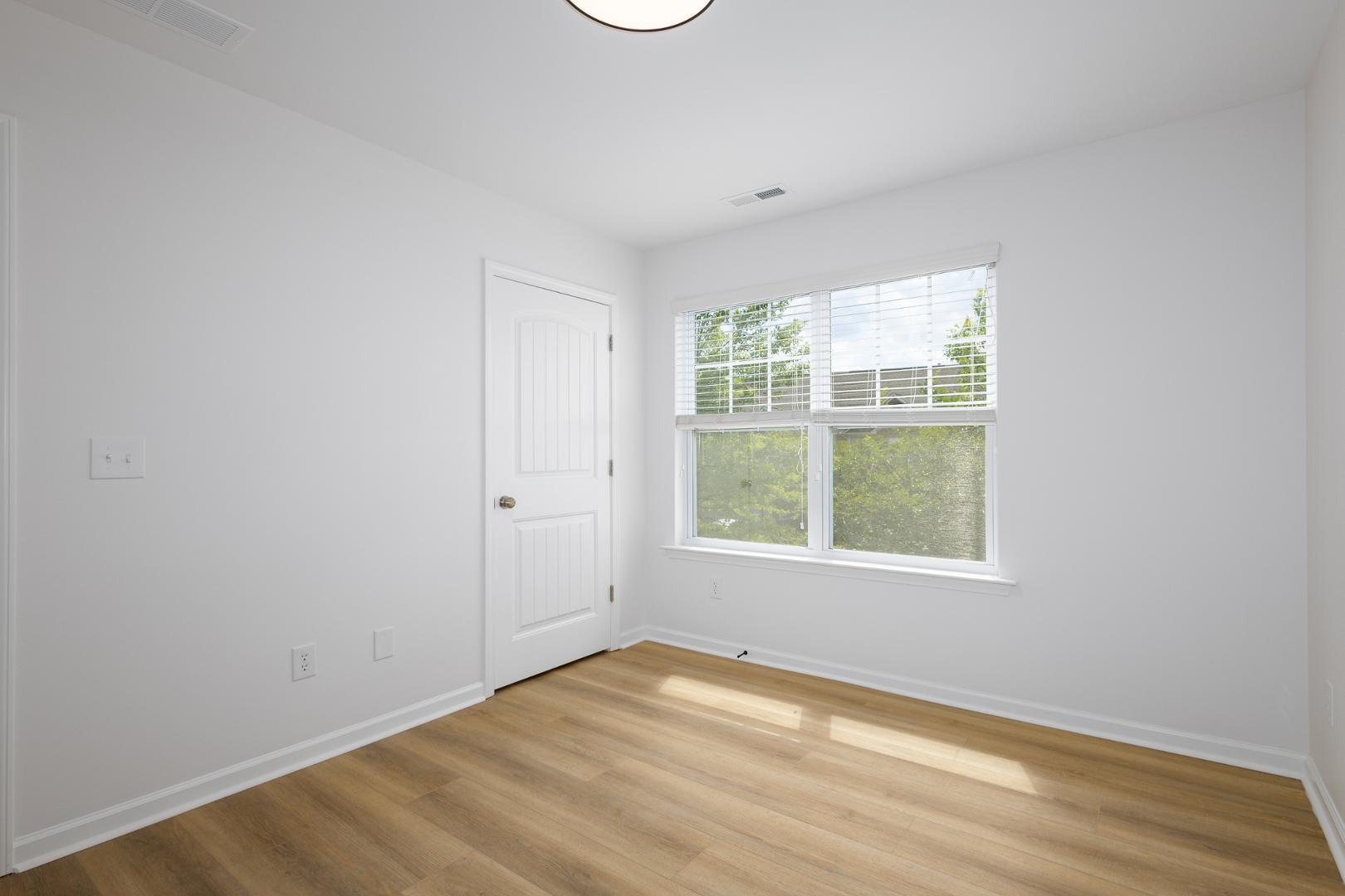 228 Skyros Loop Cary, NC 27519 - Photo 10 of 29 an empty room with wooden floor and windows